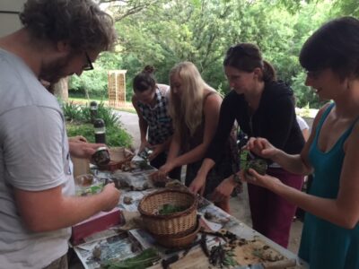 One man and four women work around a table, with baskets and plants